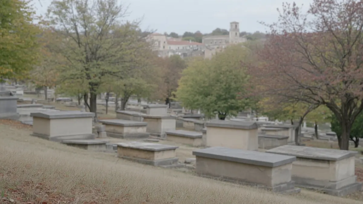 Stary cmentarz na zboczu z kamiennymi grobowcami wśród jesiennych drzew